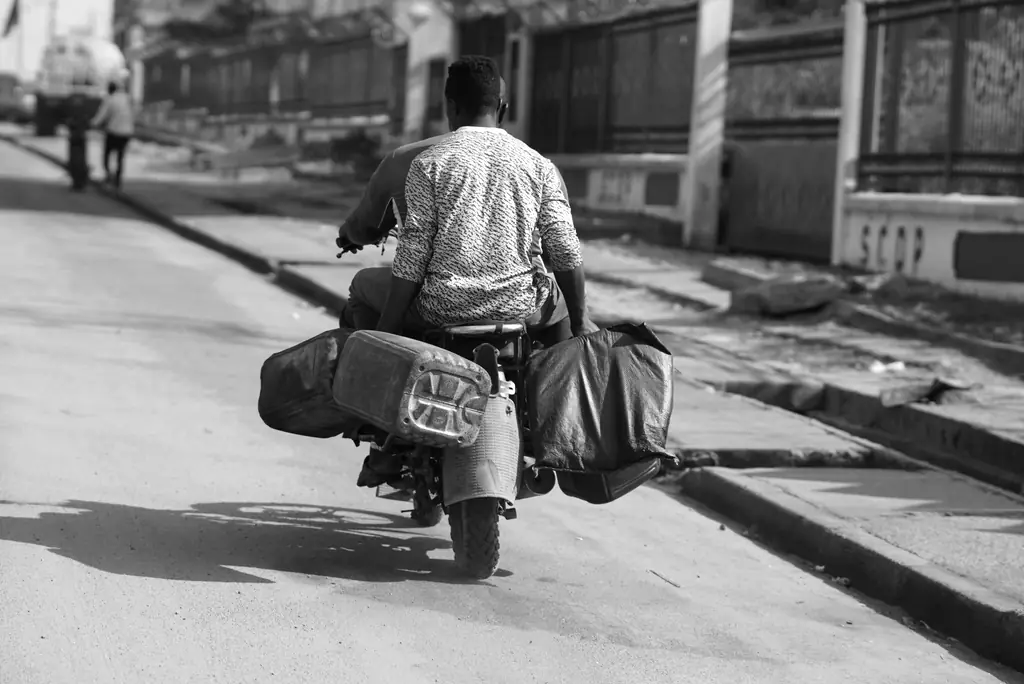 De dos, un homme sur une moto chargée de sacs, dans une rue de Douala.